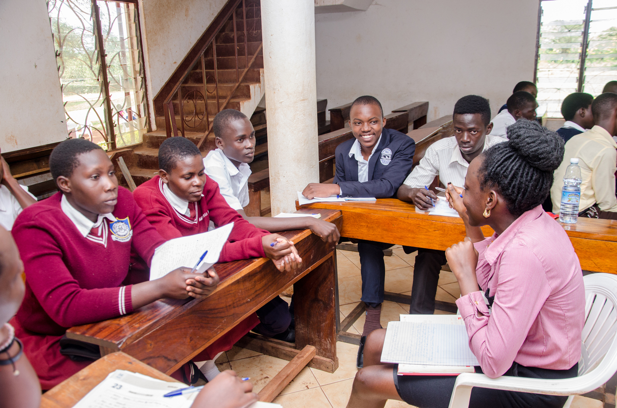 A small group of Students in uniform listening intently to a LeadMinds Africa instructor.